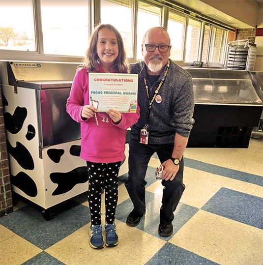 A student being recognized by Principal Emery for respectful behavior during the month of September